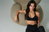 NALA Activewear Angelina black sports bra and flared leggings set; siyah spor sütyen ve İspanyol paça tayt giyen kadın model bej koltuk önünde gri fonda.