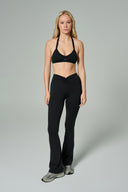 NALA Activewear black flared leggings and sports bra set; siyah İspanyol paça tayt ve spor sütyen giyen kadın model gri fonda önden tam boy duruyor.