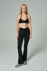 NALA Activewear black flared leggings and sports bra set; siyah İspanyol paça tayt ve spor sütyen giyen kadın model gri fonda önden tam boy duruyor.