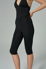 NALA Activewear black halter biker jumpsuit detail; siyah kısa paça tulumun bel ve paça kısmını gösteren yakın plan ürün görseli, gri fonda.