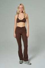 NALA Activewear brown flared leggings and sports bra set; kahverengi İspanyol paça tayt ve spor sütyen giyen kadın model gri fonda önden tam boy duruyor.